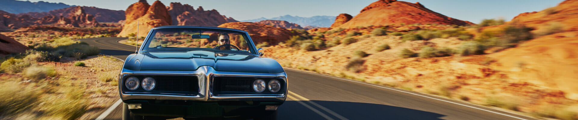 Classic Car Insurance – Get a Classic Car Insurance Quote Online Male driver in classic car on desert highway with mountains in the background
